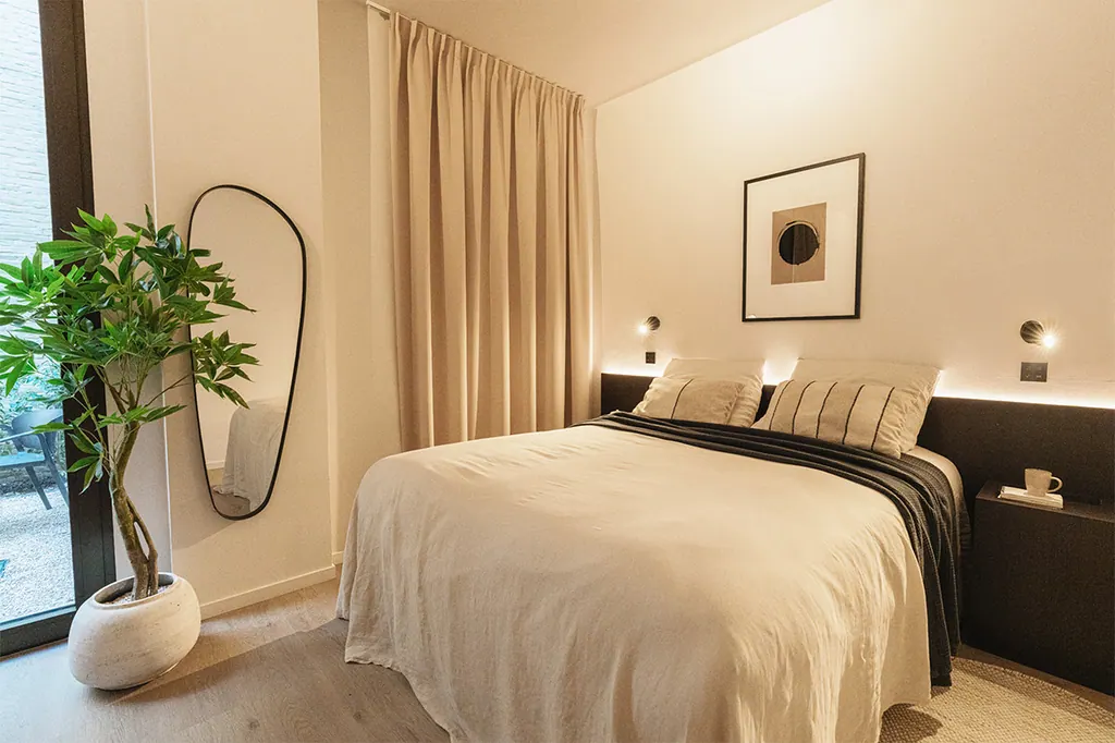 Chambre chaleureuse avec des rideaux beiges toute hauteur dans un appartement de court séjour de Raibu.