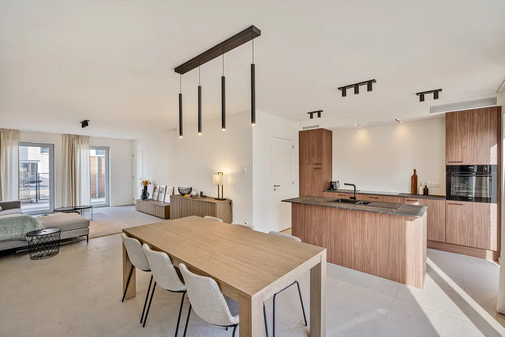 Suspensions et spots noirs au-dessus d’une cuisine en bois et d’une table à manger dans un intérieur Uptone.